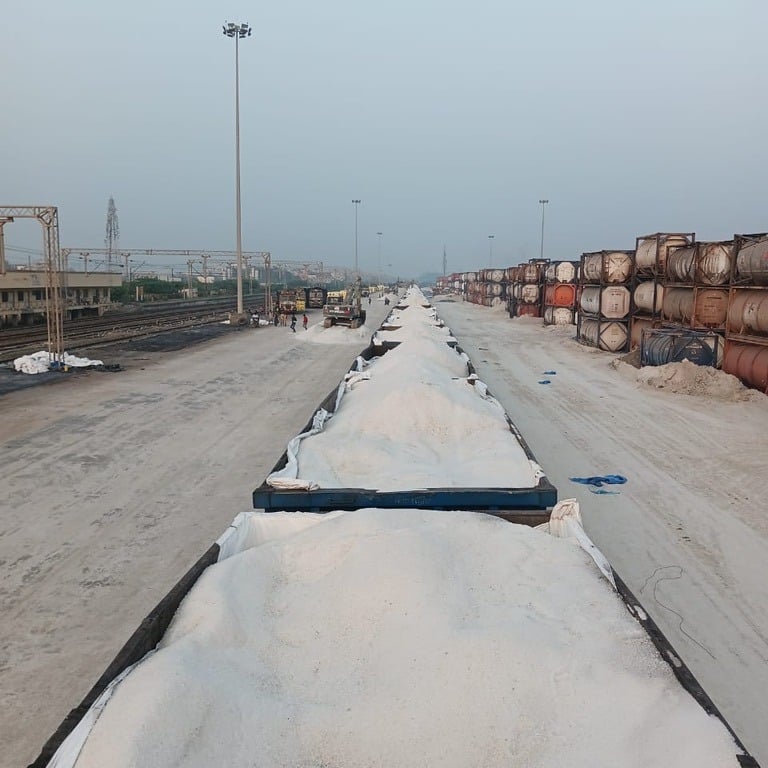 Freight train wagons filled with bulk white salt at an industrial rail yard terminal.