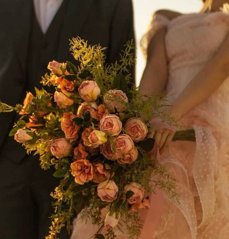 Novia con ramo de rosas en tonos durazno y verde.