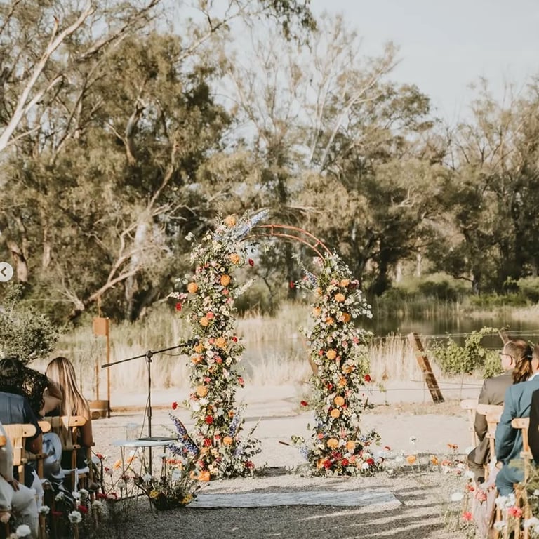 Arco floral decorando ceremonia en jardín natural.
