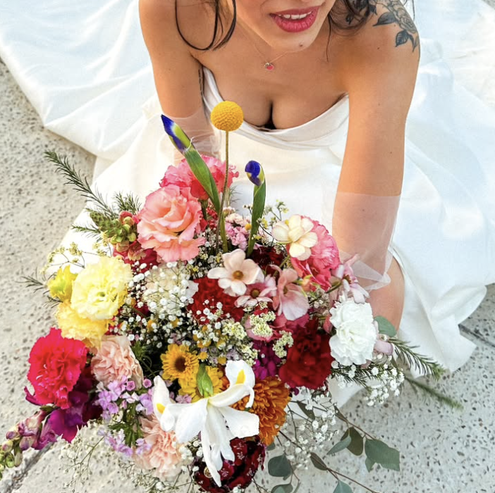 Novia sosteniendo un ramo colorido con girasoles y flores vibrantes.