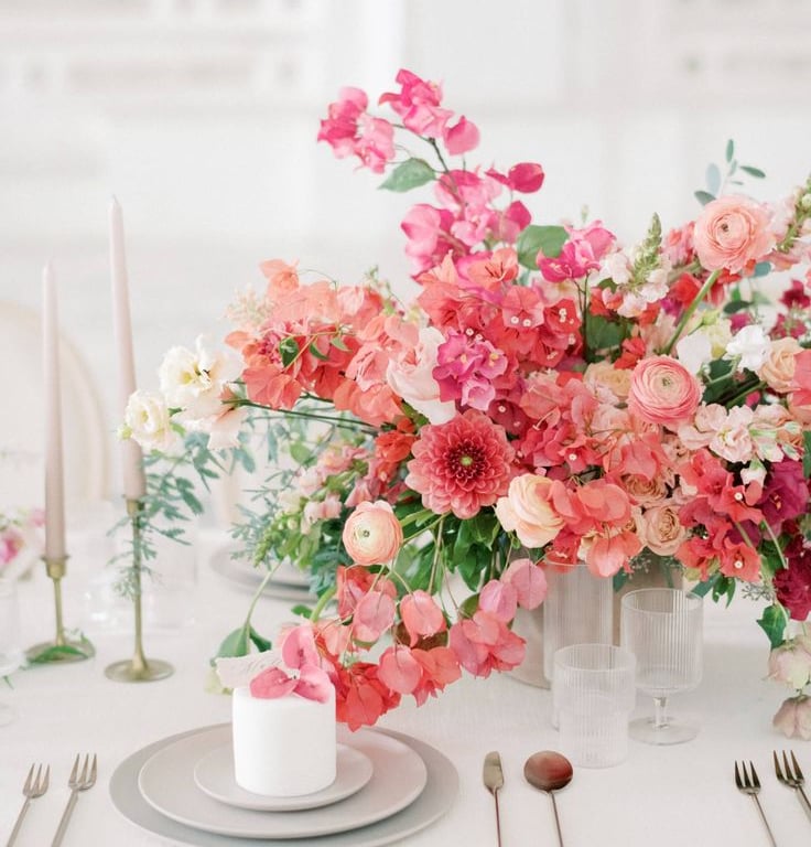 Centro floral coral y rosa con velas elegantes.