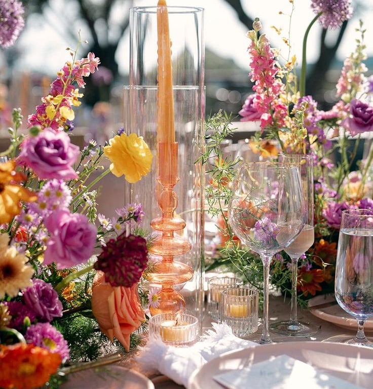 Mesa elegante con flores vibrantes y cristalería.