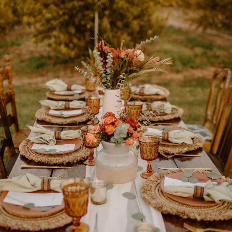 Mesa rústica de boda con platos apilados y centro floral otoñal.