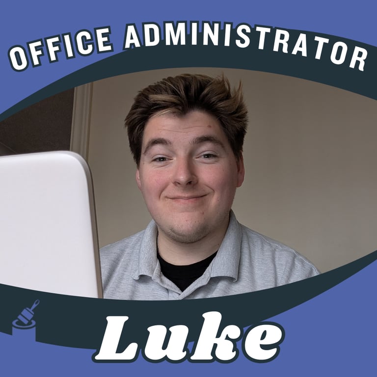 Portrait of Luke, office administrator, smiling and sat in front of a laptop.