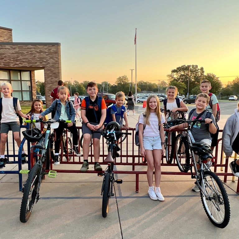 Group of kids on bikes parked at a bike rack posing for the camera