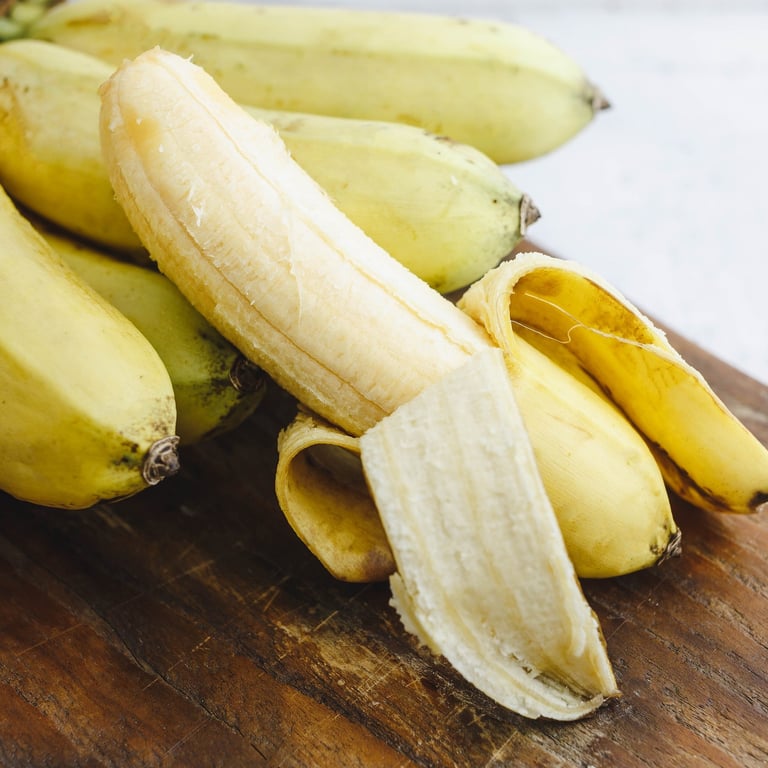 Fresh ripe bananas with one peeled on a wooden table