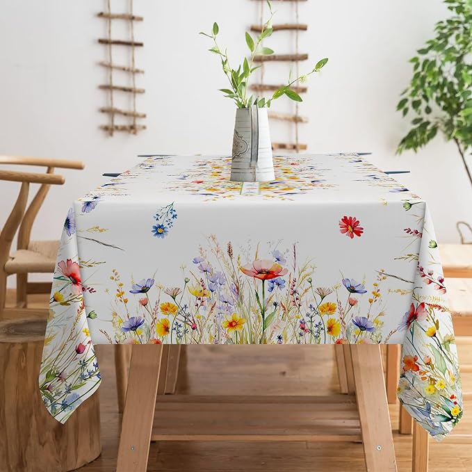 A rectangular floral tablecloth with blooming spring flowers, draped over a dining table. 