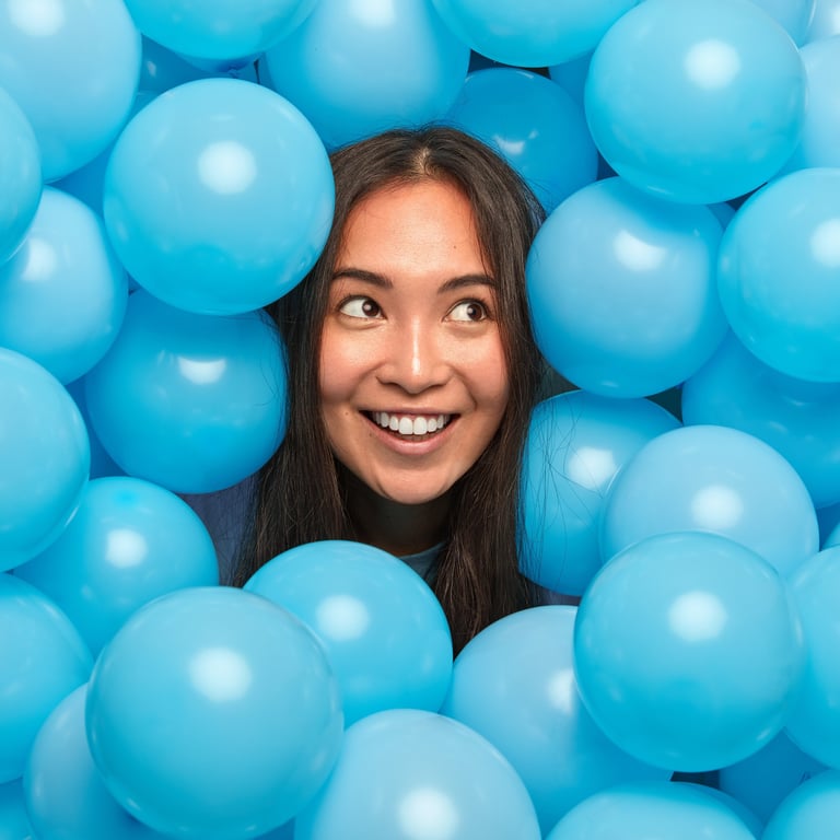 a woman in a ball pit with blue balloons