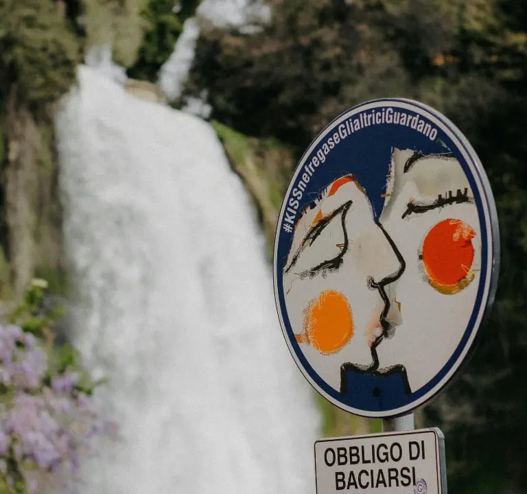 Kissing is mandatory’ sign in front of the Great Waterfall of Isola del Liri, a romantic symbol of the Italian town
