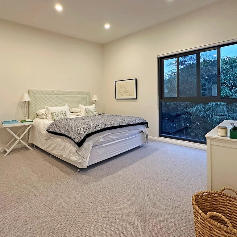 serene primary bedroom in a Maroubra architect-designed home, featuring a minimalist palette, floor-to-ceiling windows