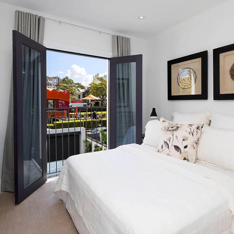 Light-filled bedroom with Juliet balcony, enhancing spatial connection in a Surry Hills terrace.