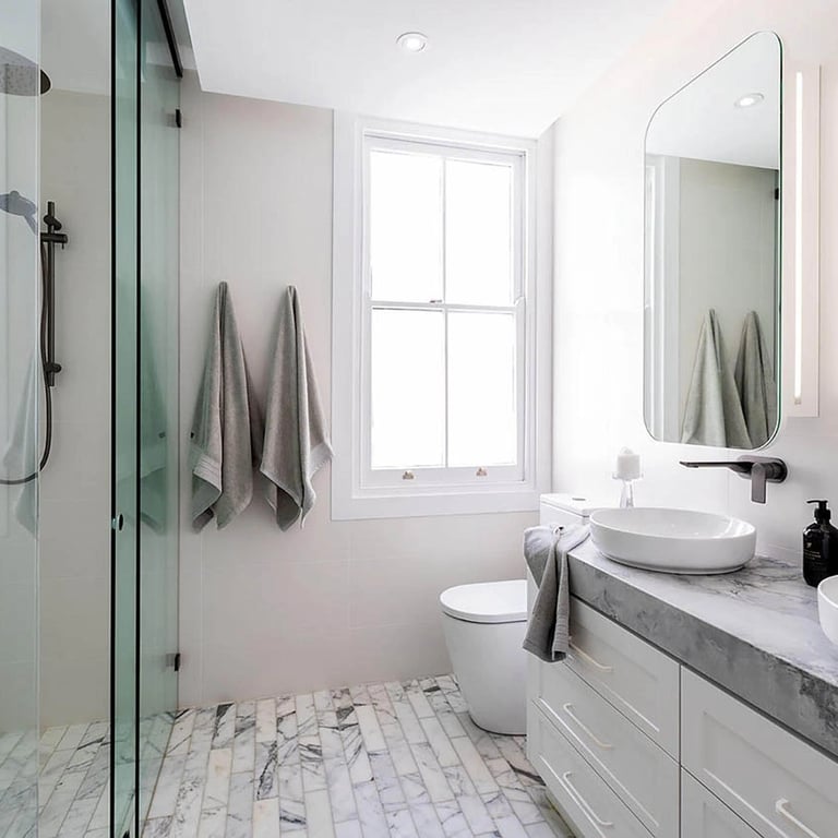 Minimalist ensuite in a heritage terrace, featuring frameless glass and tactile materiality