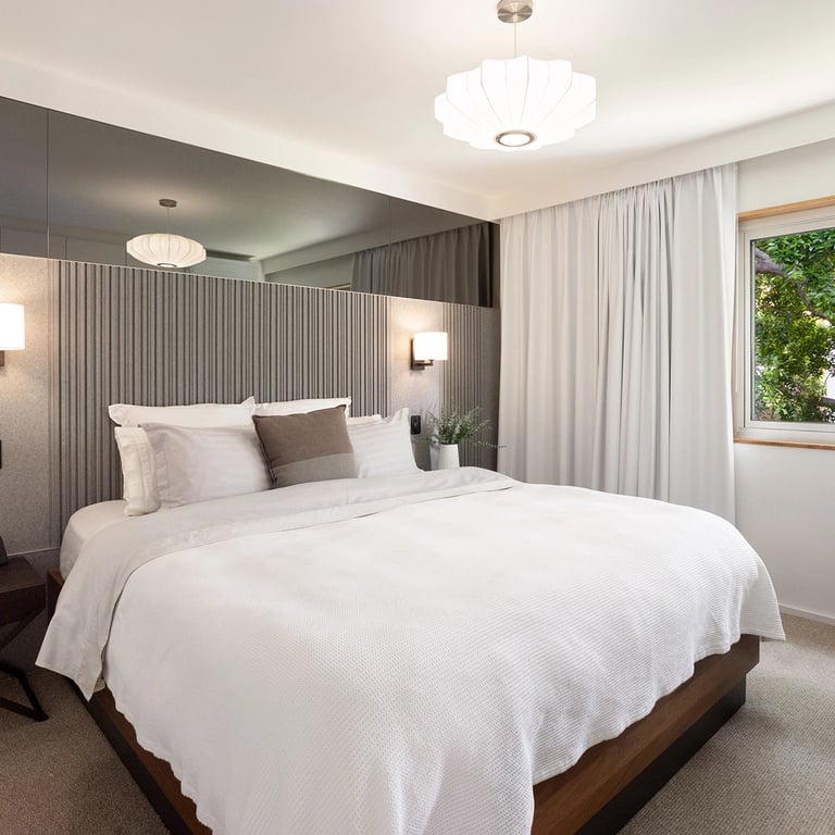 Acoustically sound bedroom in Mosman, with MCM pendant, king-sized bed and custom-made bedhead with mirror