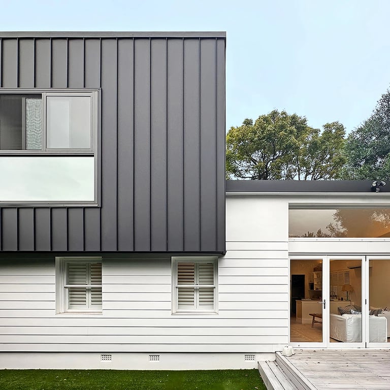 Modern two-story home in Maroubra with a striking black upper floor cantilevered over white weatherboard lower level.