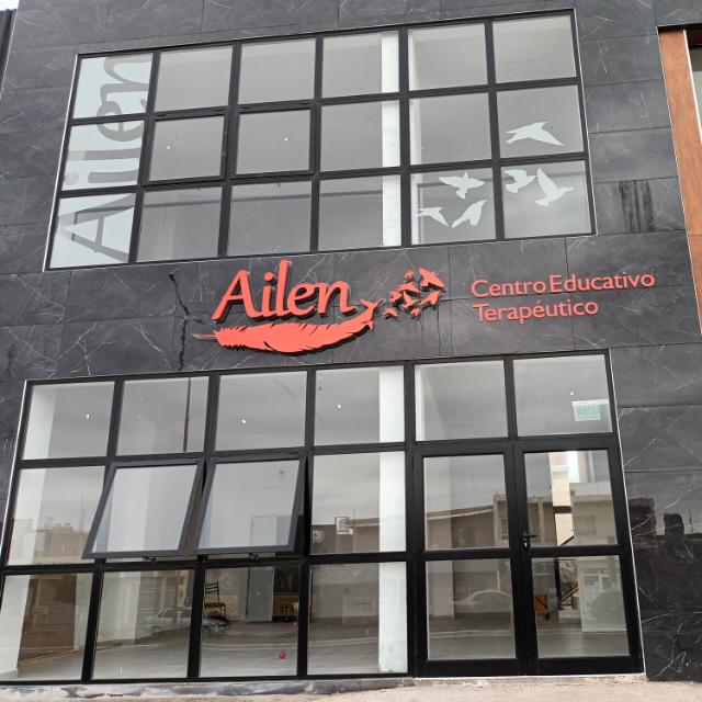 Modern building exterior of Ailen Centro Educativo Terapéutico with dark stone tiles and glass windows.