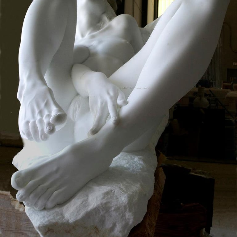 Contemporary white marble sculpture of a reclining female figure with detailed hands and feet.