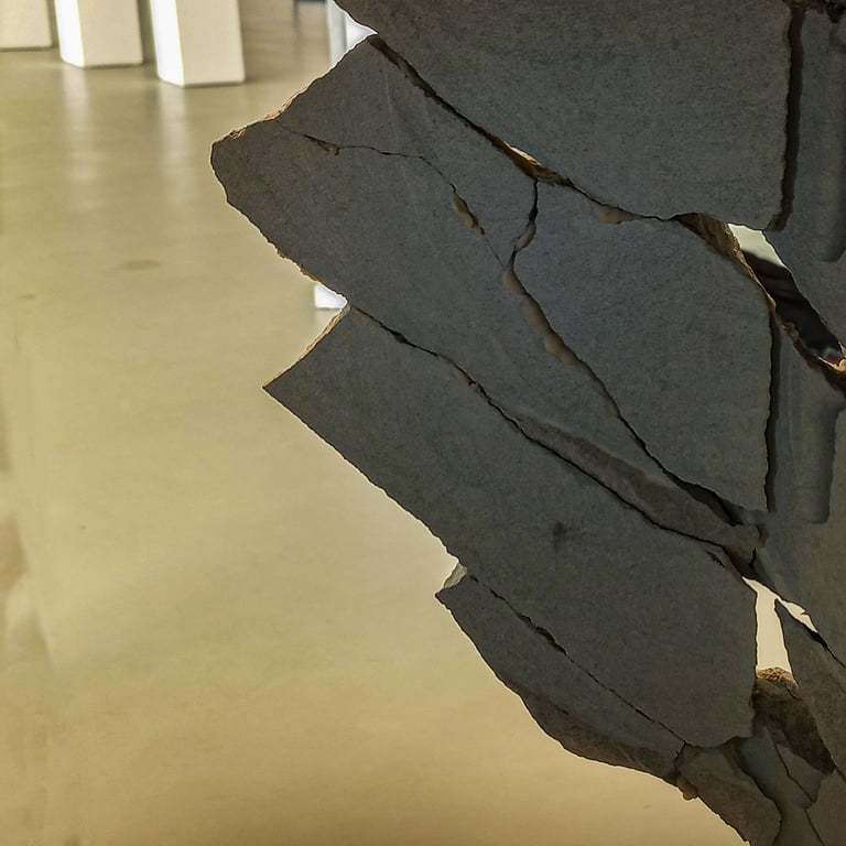 A sculpture of a block of stone broken into pieces and reconstructed like a puzzle in an exhibition