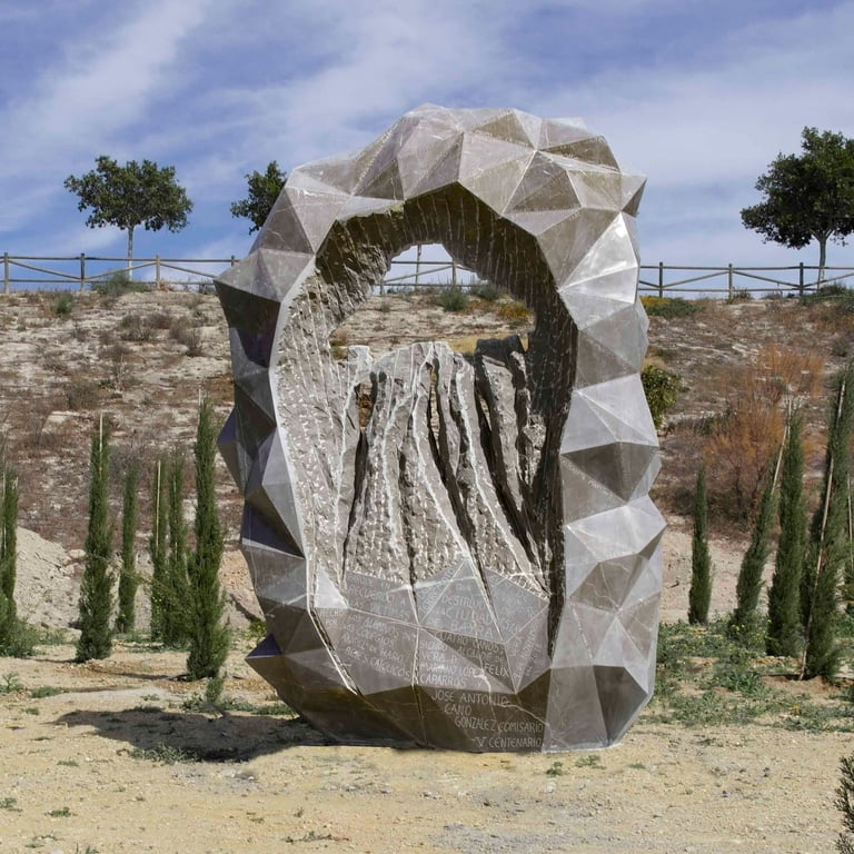 Large geometric hollow stone sculpture outdoors with cypress trees and blue sky background.