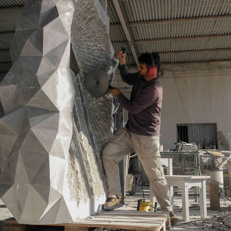 Modern geometric stone sculpture in a park at sunset with palm trees and a basketball court.