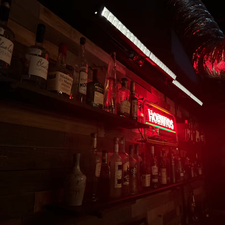 Bar shelf with liquor bottles and red Hornitos neon sign at Grayfox Studios