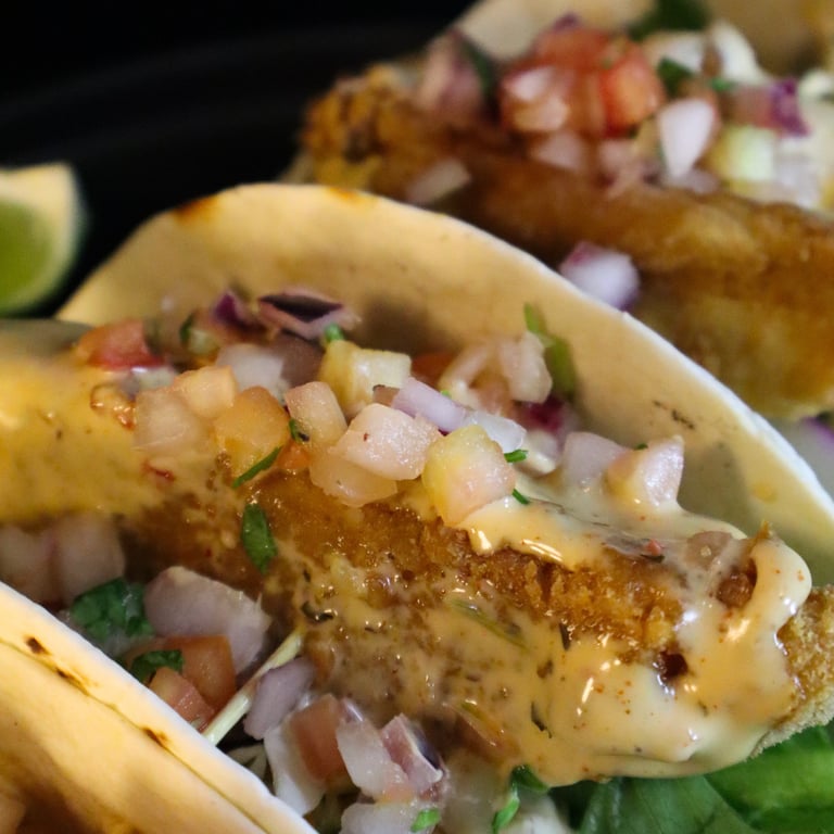 a plate of fish tacos with a lime wedged fish tacoil