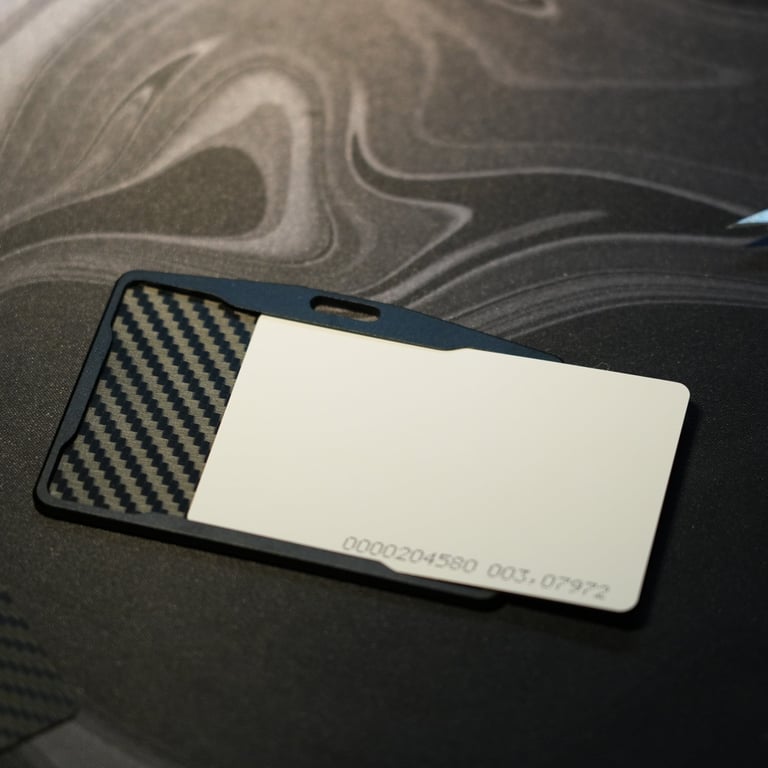 A minimalist carbon fiber ID card holder with a white proximity card on a black desk mat.