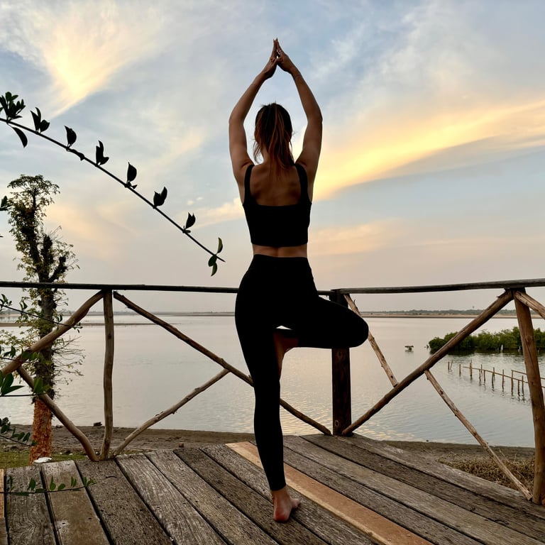 Pose de yoga avec vue sur le bolong et le début de la mangrove depuis le boutique hôtel Maison Fimela situé au coeur du Sine 