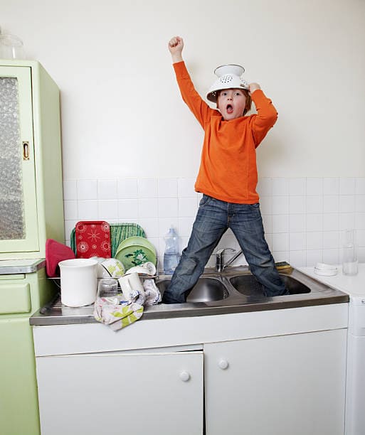 a young boy standing in a kitchen sink