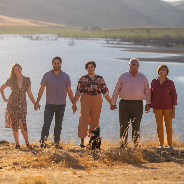Family portrait photographer in Visalia capturing a group by a lake at sunset.