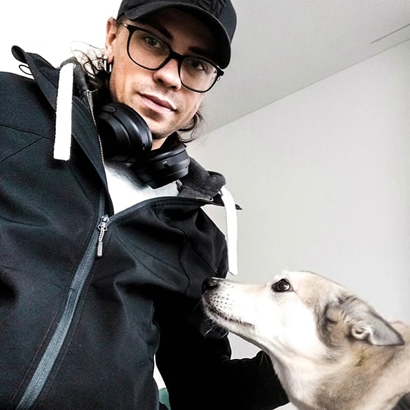 lächelnder Mann mit Brille und schwarzer Baseballkappe mit grauem Hund