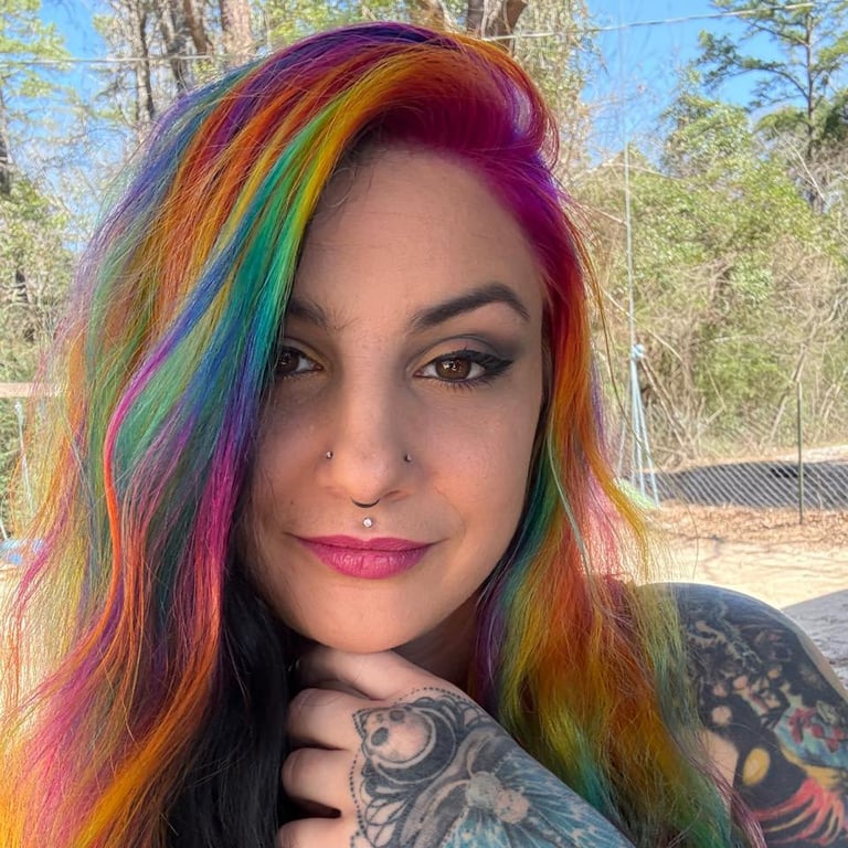 Beautiful woman that is tattoo artist with colorful hair and piercings on her chest
