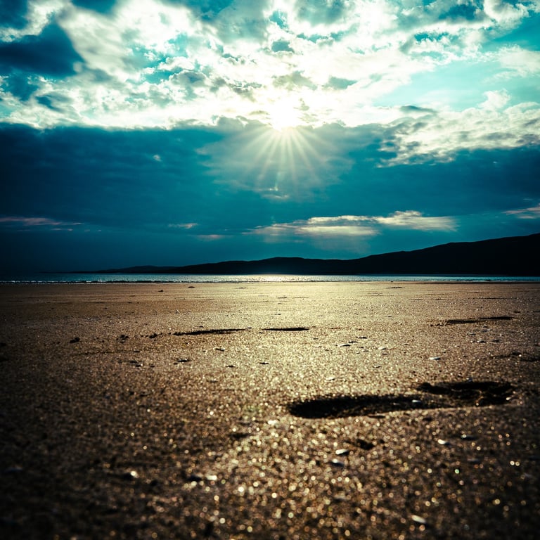 Le soleil transperce les nuages, illuminant la plage de lumière dorée, tandis que des empreintes de pas mènent vers l’horizon