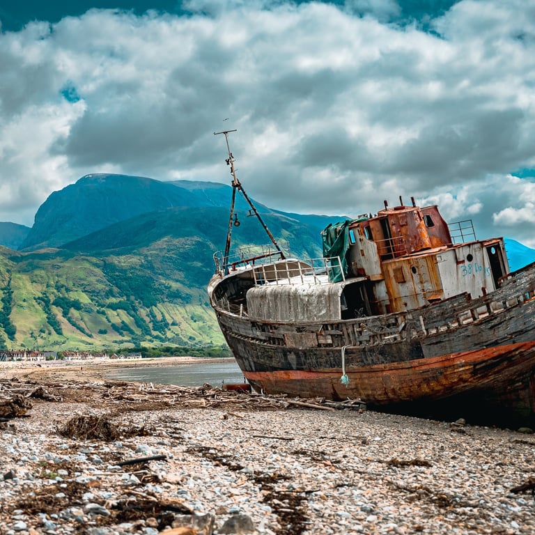 L’épave de Corpach repose sur la plage encadrée par les montagnes imposantes, créant une scène à la fois mystique et paisible