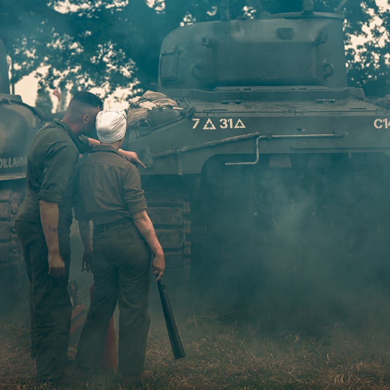 Deux mécaniciens, dont une femme en turban blanc, réparent un char Sherman, hommage aux contributions des femmes en guerre.