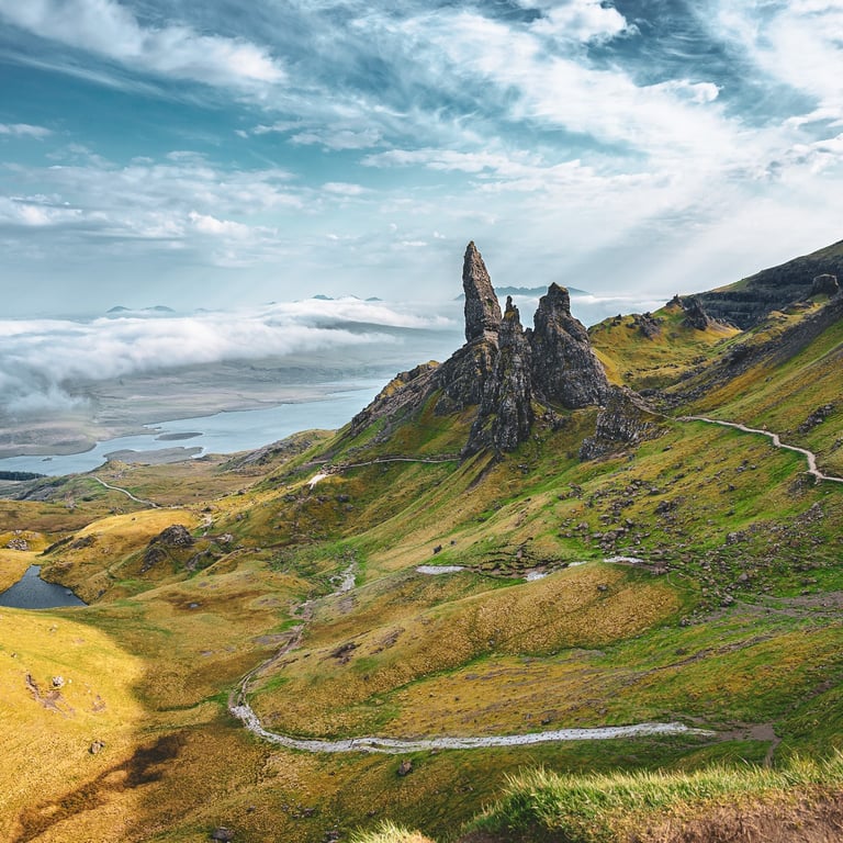L'Old Man of Storr se dresse majestueusement au milieu des collines verdoyantes de l'île de Skye, sous un ciel dramatique.