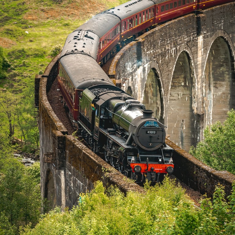 Le train Poudlard Express traverse majestueusement le viaduc de Glenfinnan, entouré de verdure luxuriante.