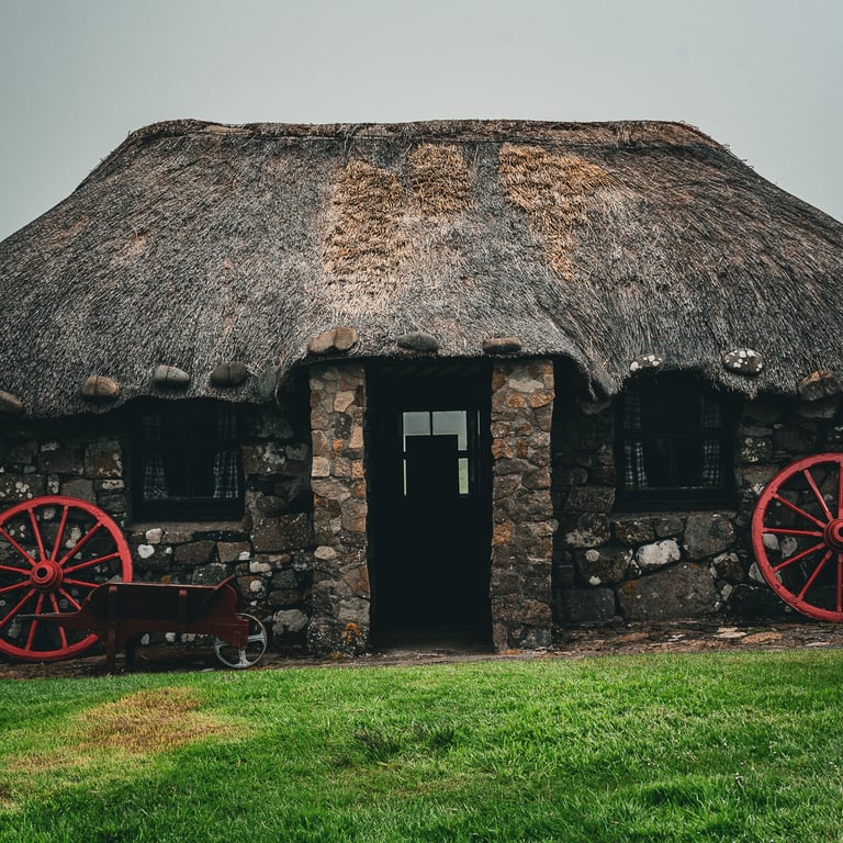 Chaumière traditionnelle en pierre au Skye Museum of Island Life, avec des roues rouges, sur fond de brume écossaise.
