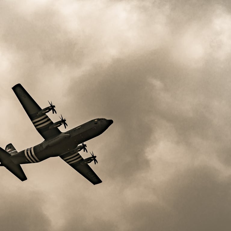 Photo sépia d'un C-130 Hercules en vol lors des commémorations du Débarquement, symbole du parachutage des troupes alliées.