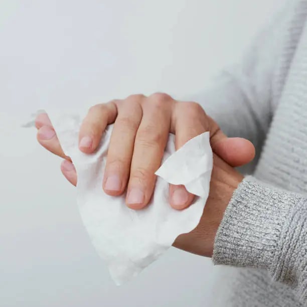 a person cleaning his hands with a wet tissue towel