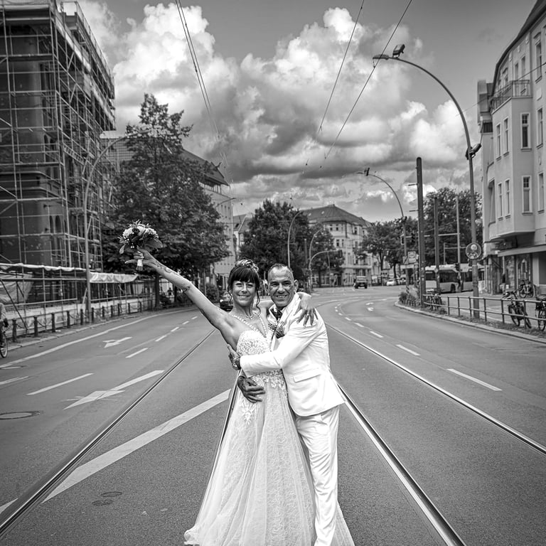Ein schwarz-weißes Foto eines Hochzeitspaares, das sich umarmt und in die Kamera lächelt, während es in der Mitte einer leere