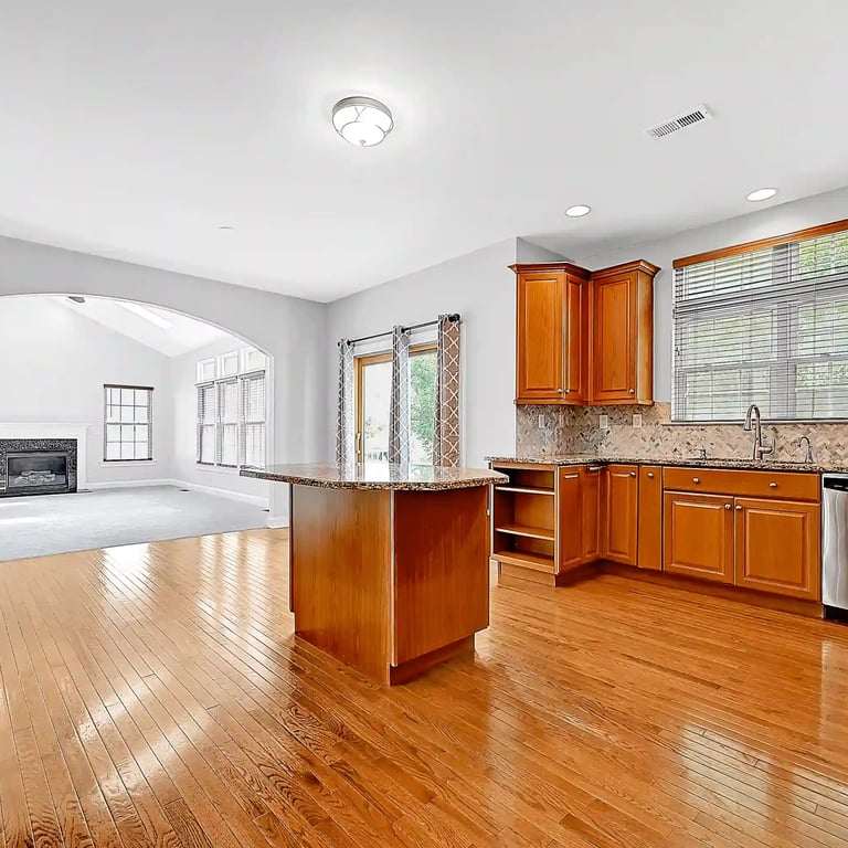 Luxury kitchen with island, hardwood floors, and open living space—ideal for showcasing upscale real estate listings