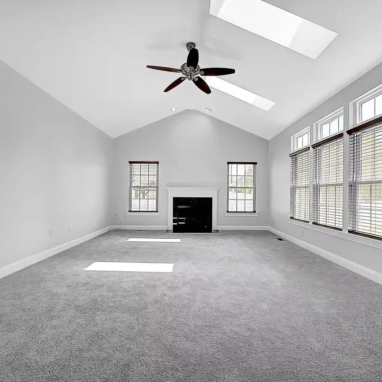 Spacious living room with vaulted ceilings, skylights, and large windows—perfect for showcasing natural light