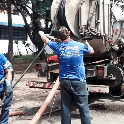 técnico uniformizado e prestando serviço de hidrojateamento com caminhão especializado