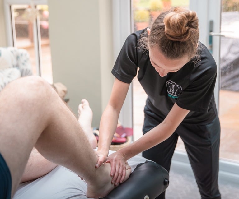 Sports Therapist conducting an ankle injury assessment on a client