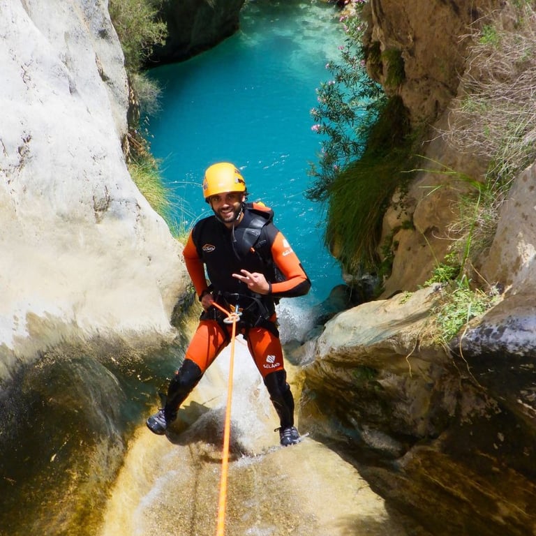 Persona realizando rápel en el barranco de Río Verde, rodeada de formaciones rocosas y agua clara