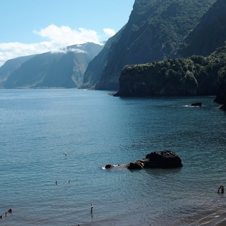 Black sand beach at Praia do Porto do Seixal with cliffs and calm sea