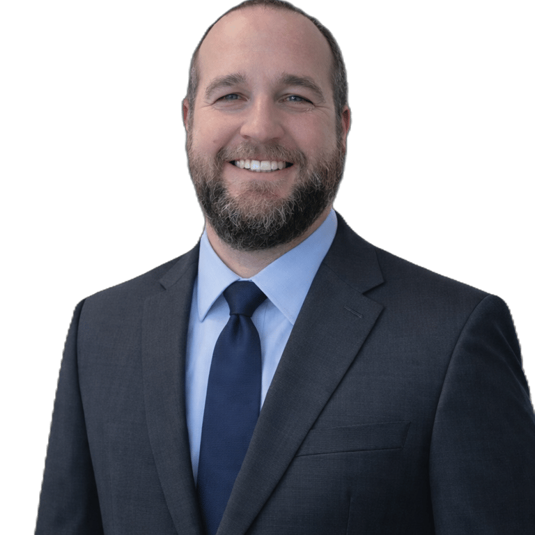 Professional headshot of a smiling man with a beard wearing a grey suit and blue tie.