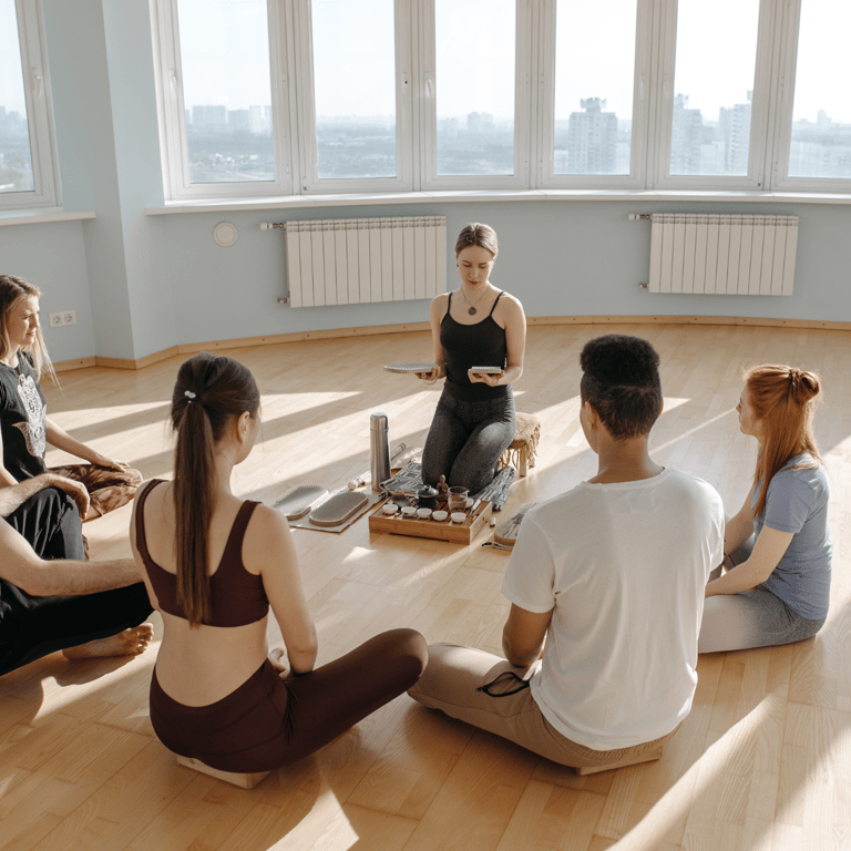 Groupe of five employees sitting in circle on the floor, in a corporate setting, with an instructor.