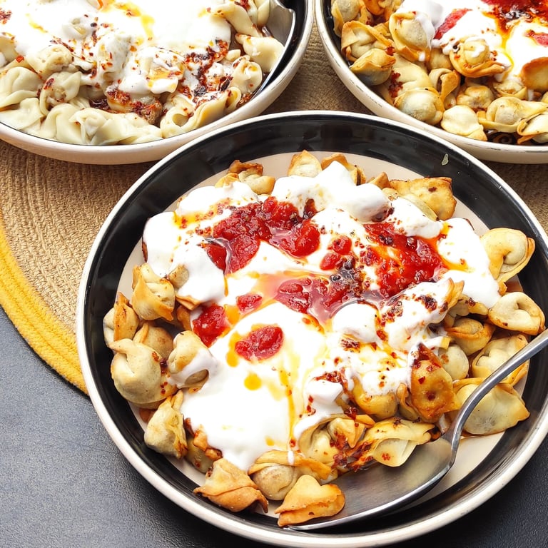 bir tabak yoğurt ve domates soslu mantı