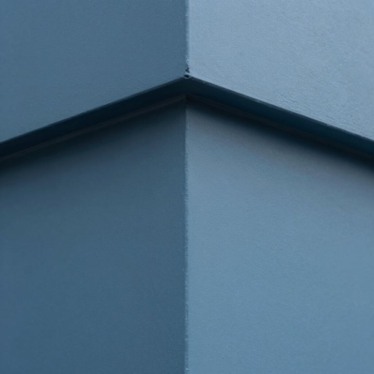 A close-up of a perfectly finished outside corner of a wall, showing sharp lines and smooth Muted Blue surfaces.